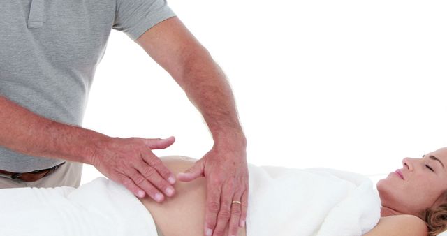 Chiropractor adjusting patient's abdomen for therapeutic treatment aimed at relieving pain or improving health. Ideal for use in articles, blogs, or advertisements related to alternative medicine, chiropractic services, physical therapy, wellness clinics, or holistic health practices.
