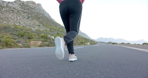 Woman Jogging on Scenic Mountain Road for Fitness and Health