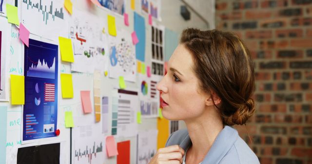 Businesswoman Analyzing Marketing Charts with Sticky Notes on Wall - Download Free Stock Images Pikwizard.com