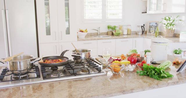 Streamlined modern kitchen featuring a variety of fresh vegetables and spices arranged on a countertop, ready for meal preparation. Saucepans and a frying pan stand on a stove, eliciting a sense of home cooking and culinary creativity. Ideal for promotional content in home design magazines, cooking blogs, or lifestyle branding materials.