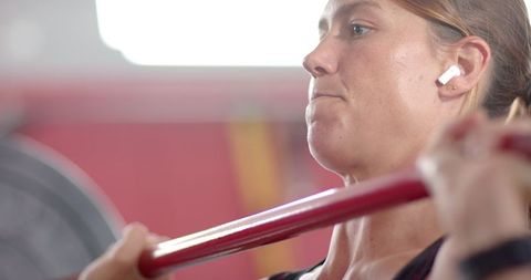 Young Woman Focused on Lifting Weights in Modern Gym