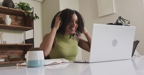 African american woman adjusting headphones while working remotely from home office desk