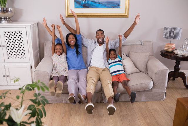 Portrait of happy family cheering while sitting on sofa at home