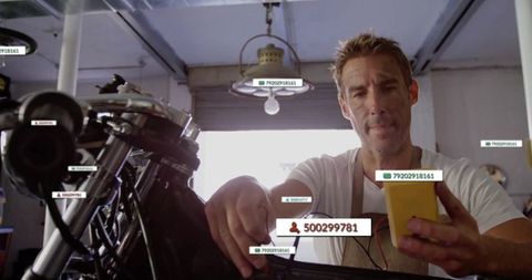 Mechanic examining motorcycle engine with smartphone and expertise