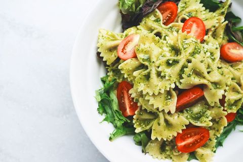 Farfalle pesto salad featuring cherry tomatoes and mixed greens