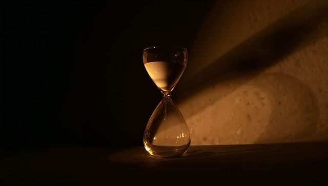 Glass hourglass casting shadows creating timeless ambiance