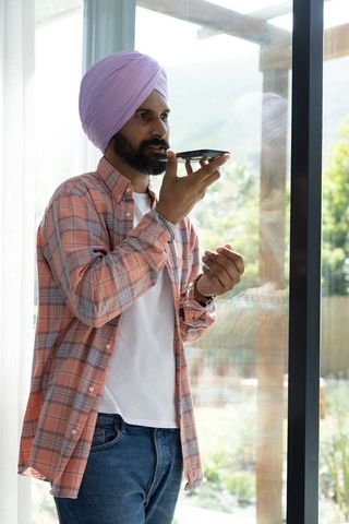 Indian man in lilac turban using smartphone voice command