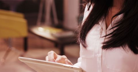 Young Asian Woman Engaged with Tablet Technology Indoors