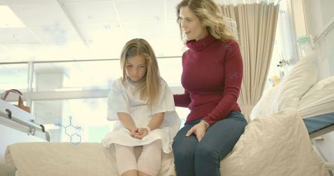 Mother comforting daughter on hospital bed showing compassion, support and resilience