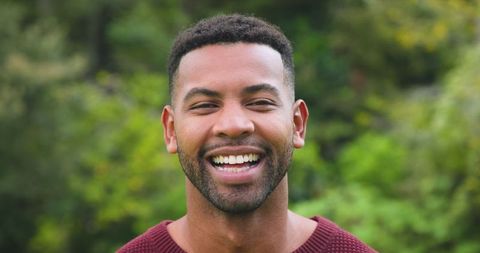Smiling African American Man in Outdoor Setting with Greenery