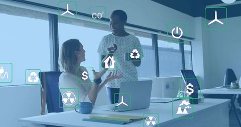 Coworkers collaborating on sustainability strategy with energy icons in open-plan office