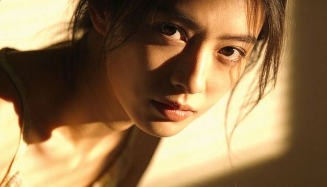 Golden hour portrait of asian woman gazing toward viewer with soft warm light and minimalist mood