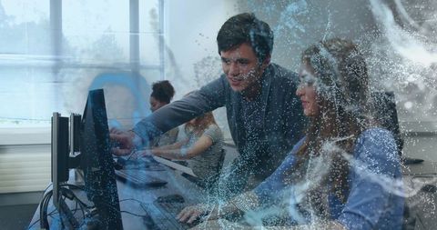 Mentor guiding trainee at computer with digital particle overlay in modern classroom