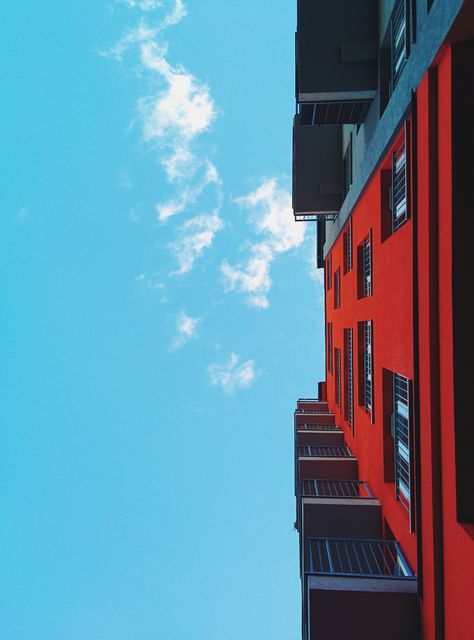 This photo of a colorful residential building against a bright blue sky emphasizes modern urban living and vibrant architectural design. It is perfect for use in real estate, urban planning, architectural portfolios, and design blogs. Its striking colors and clear details also make it suitable for backgrounds, websites, and promotional materials.
