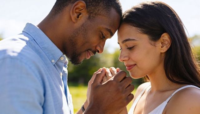 Intimate couple holding clasped hands in sunlit meadow outdoor romance and affection warmth