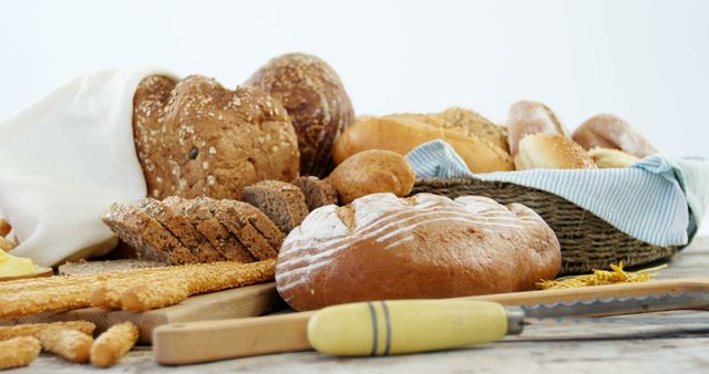 A variety of freshly baked breads and rolls are displayed on a table, with copy space. The scene conveys the abundance and diversity of bread products available, suggesting a setting of a bakery or a market.