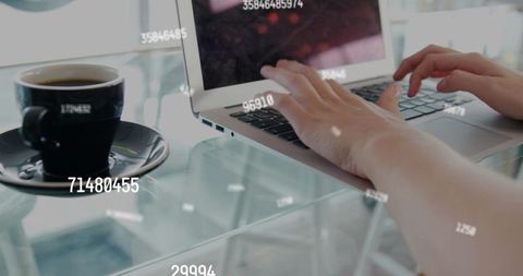 Typing on laptop with coffee and floating numeric overlays in modern cafe coworking scene