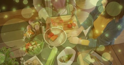 Couple preparing fresh vegetable salad overhead, kitchen meal prep with bokeh lights