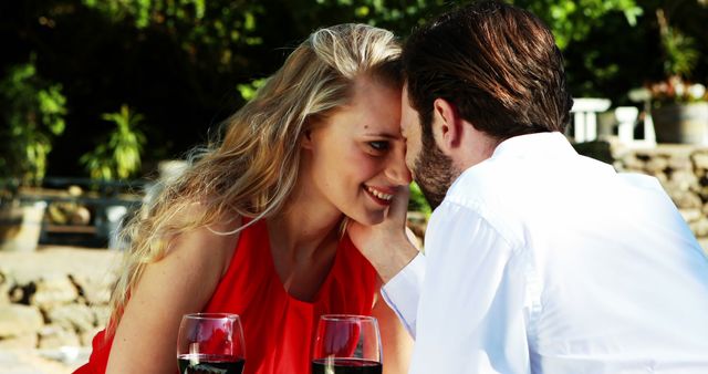 A young Caucasian couple enjoys a romantic moment over glasses of wine, with copy space. Their intimate gaze suggests a deep connection and a celebration of love or a special occasion.
