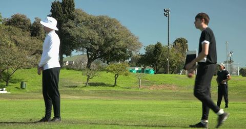 Cricket Players Analyzing Game Strategy on Bright Day Outdoors