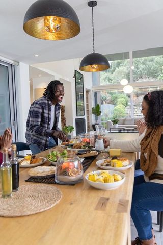 African american friends sharing hearty dinner in sunlit modern open-plan dining