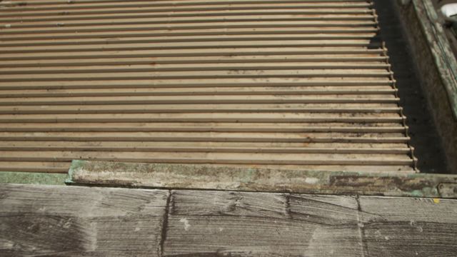 High angle scene focuses on corrugated metal rooftop of building, gives weathered and textured look under bright sun. Useful for urban architectural projects, roofing materials, and industrial-themed visuals. Ideal for background or demonstrating rooftop textures.