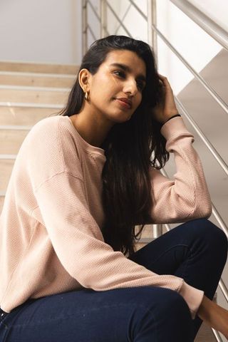 South Asian Woman Relaxing in Minimalist Stairwell Reflecting