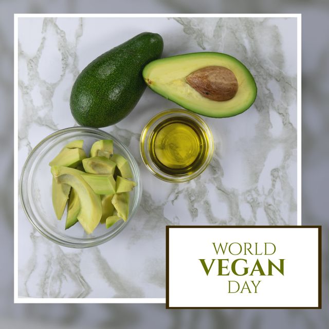 Digital composite of avocado slices and oil on marble table with world vegan day text. Fruit, veganism, organic, food, healthy, support and celebration concept.
