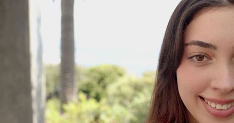 Woman Smiling Outdoors with Botanical Background