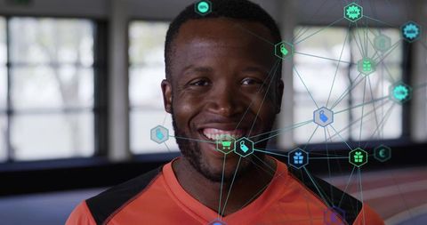 Smiling athlete in orange shirt with augmented reality data overlay on indoor track