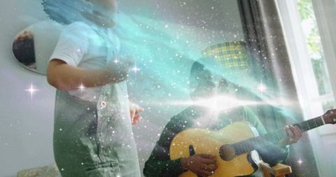 Dad playing guitar while toddler dancing in sunlit living room with cosmic nebula overlay