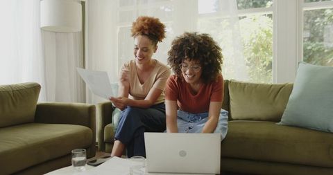 African American Women Collaborating on Laptop and Documents in Bright Living Room