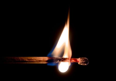 Extreme macro close-up burning matchstick with blue and orange flame on black background
