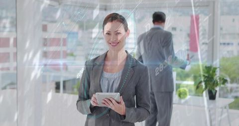 Businesswoman reviewing tablet with holographic analytics overlay in modern glass office
