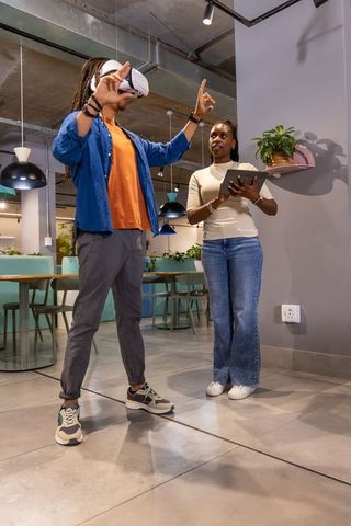 African American Coworkers Trying VR Headset While Tracking Progress on Tablet