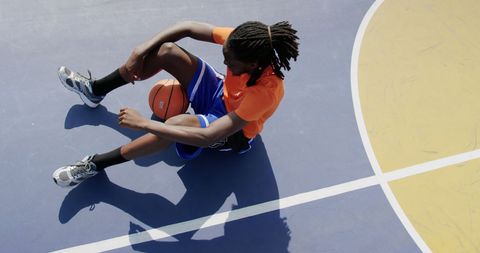 Tired basketball player relaxing on asphalt court