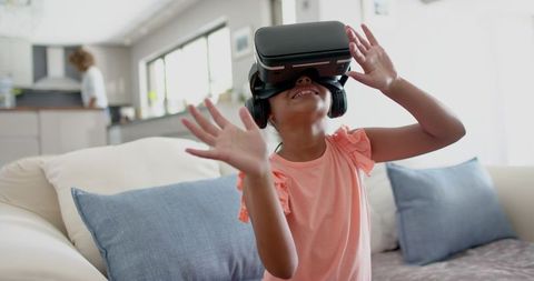 Joyful Young Girl Exploring Virtual Reality in Modern Living Room