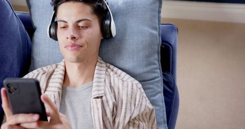 Relaxed Man with Headphones Lounging on Cozy Blue Sofa - Download Free Stock Images Pikwizard.com