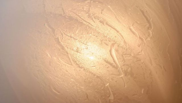 Beige cream plaster ceiling showing trowel texture and central warm light glow