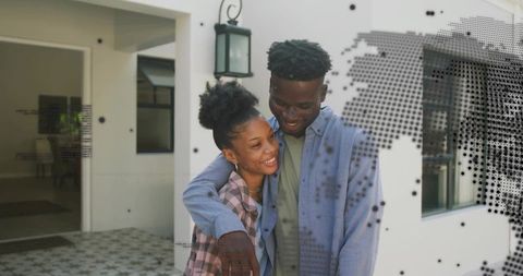 Young couple embracing on modern front porch with lantern, smiling in warm home moment