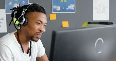 Focused male executive with headphones working on computer screen tasks