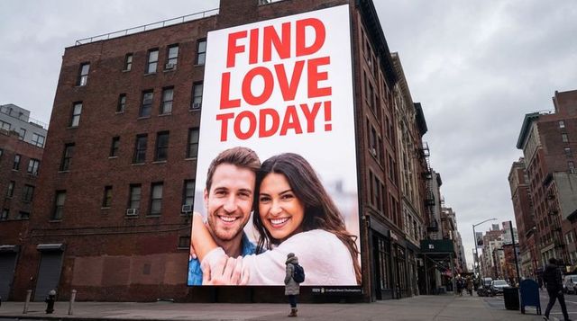 Urban billboard advertising dating app with smiling couple and pedestrian walking downtown