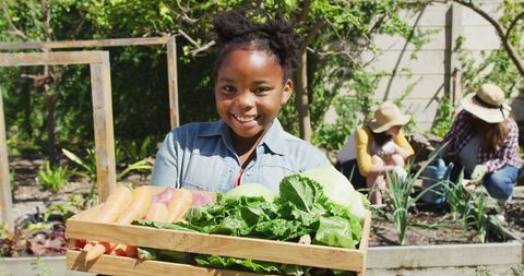 Joyful Girl Harvesting Fresh Vegetables in Garden