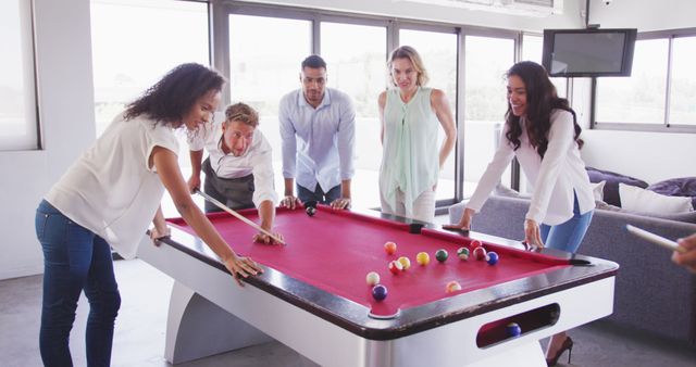 Multi-ethnic group of business colleagues at the office of a creative business, playing pool together, in slow motion. business people and work colleagues at a busy creative office.