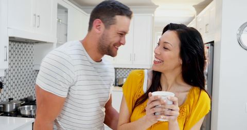 Interracial Couple Enjoys Morning Kitchen Chat with Coffee