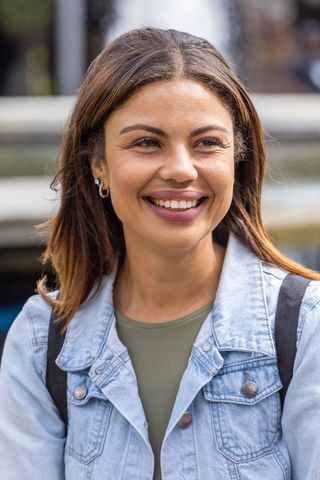 African american woman smiling and looking away on city street in denim jacket, backpack