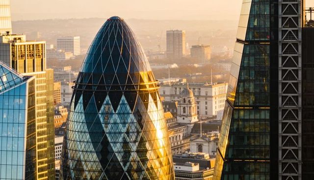 Gherkin tower reflecting golden light over london skyline with historic domes