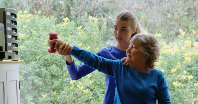 Caregiver helps elderly woman with weight training exercise outside. Perfect for themes of elderly care, physical fitness for seniors, and health care. Suitable for websites, brochures, and campaigns focusing on active aging, caregiving services, and senior health.