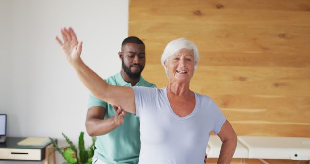 Image of happy african american male physiotherapist examining caucasian senior woman. seniors health and nursing home lifestyle concept.