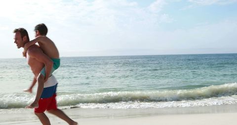 Father Piggybacking Son on Sandy Beach - Download Free Stock Images Pikwizard.com